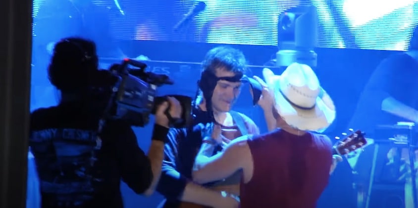 Kenny Chesney goofs off with a band member while singing a David Allan Coe song with Uncle Kracker