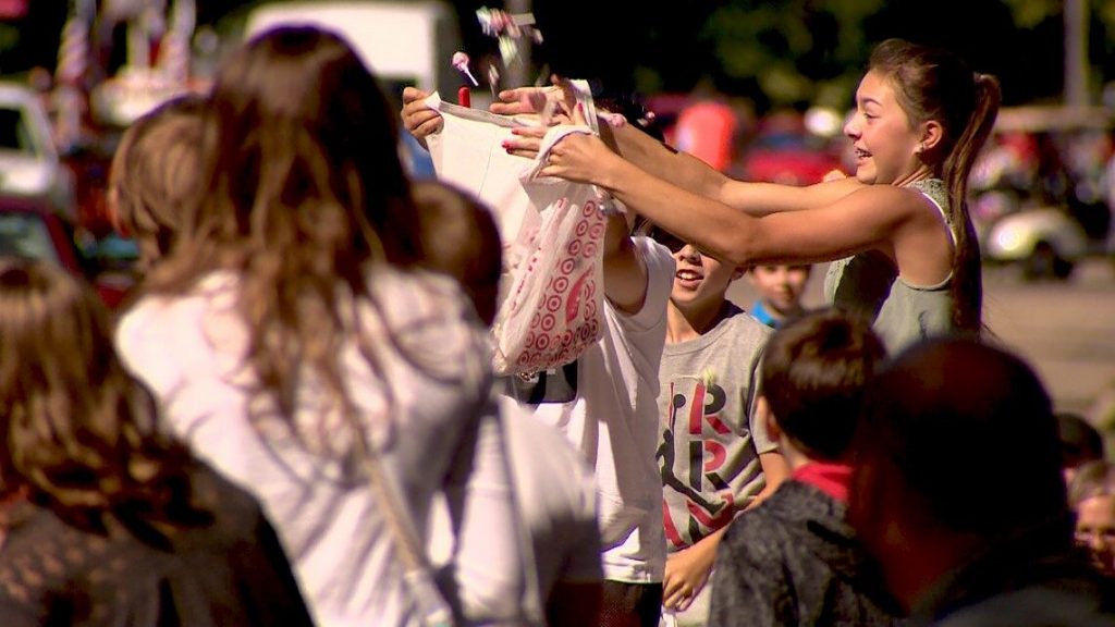 A paradegoer catches candy dropped from a combine in a plastic bag.