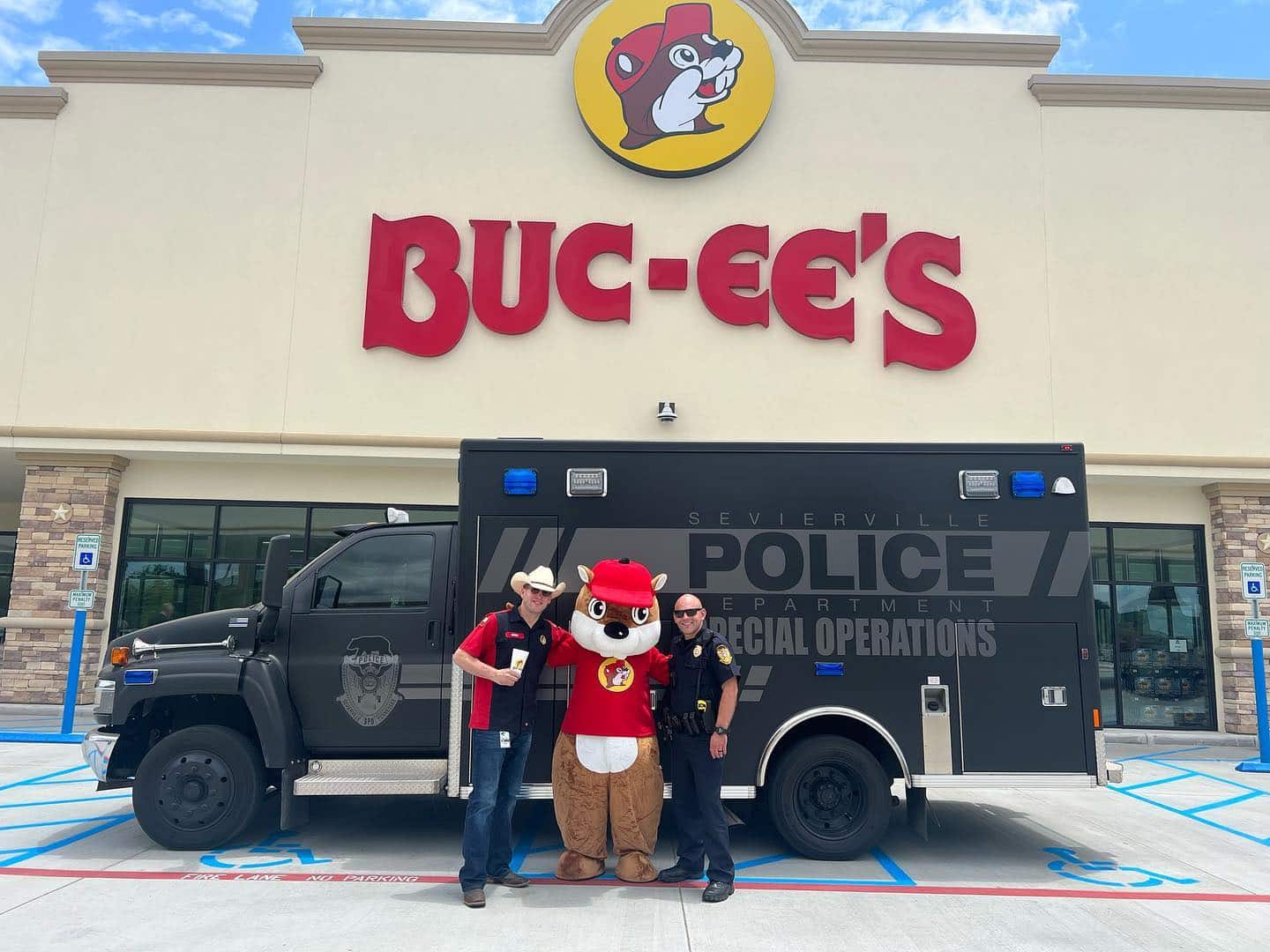 Police officers stand outside Buc-ee's taking a picture with the mascot.
