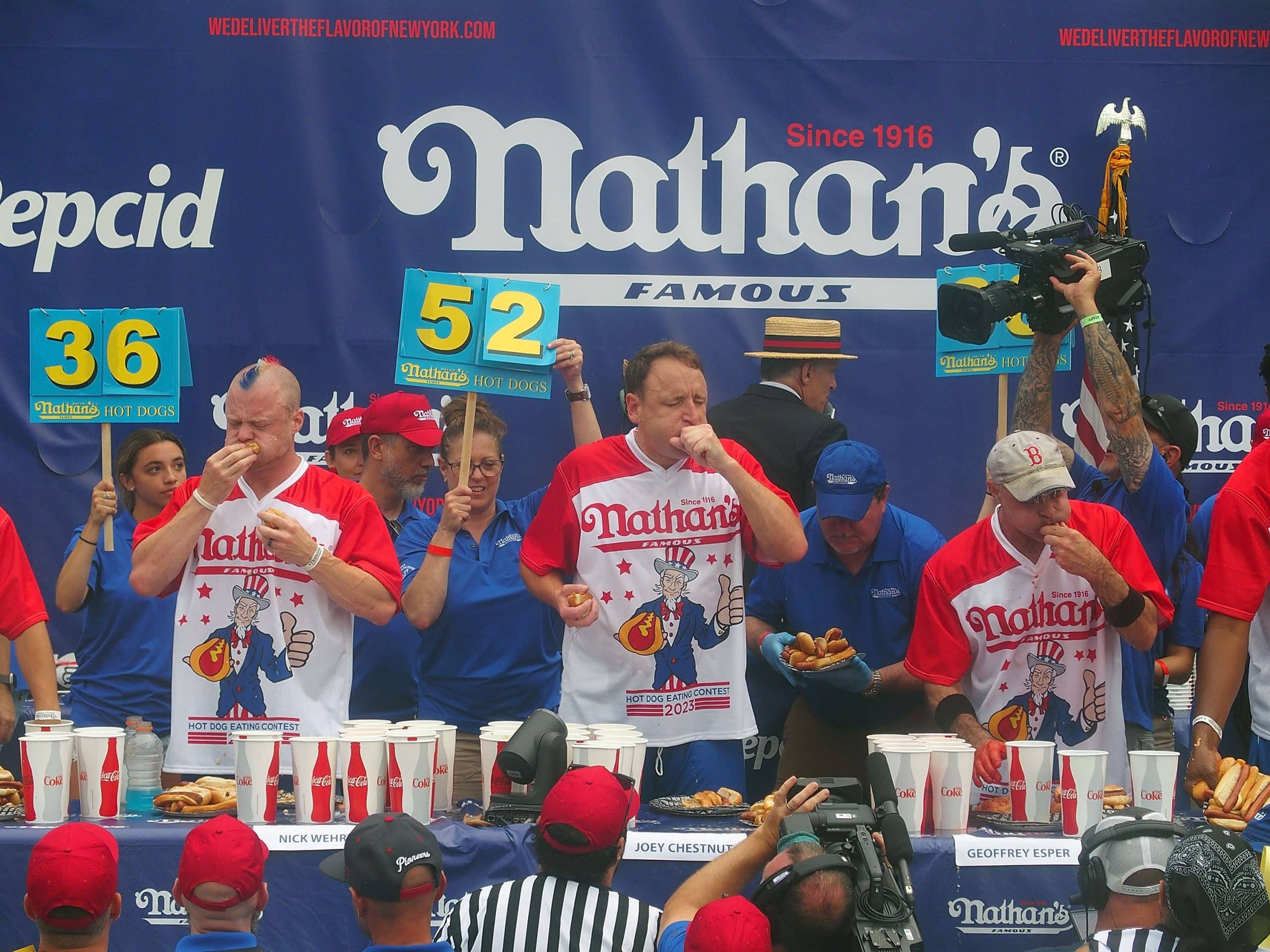 NEW YORK, NY - JULY 04: Defending champion Joey Chestnut (C) competes in the 2023 Nathan's Famous International Hot Dog Eating Contest at Coney Island on July 4, 2023 in New York City. (Photo by Bobby Bank/Getty Images)