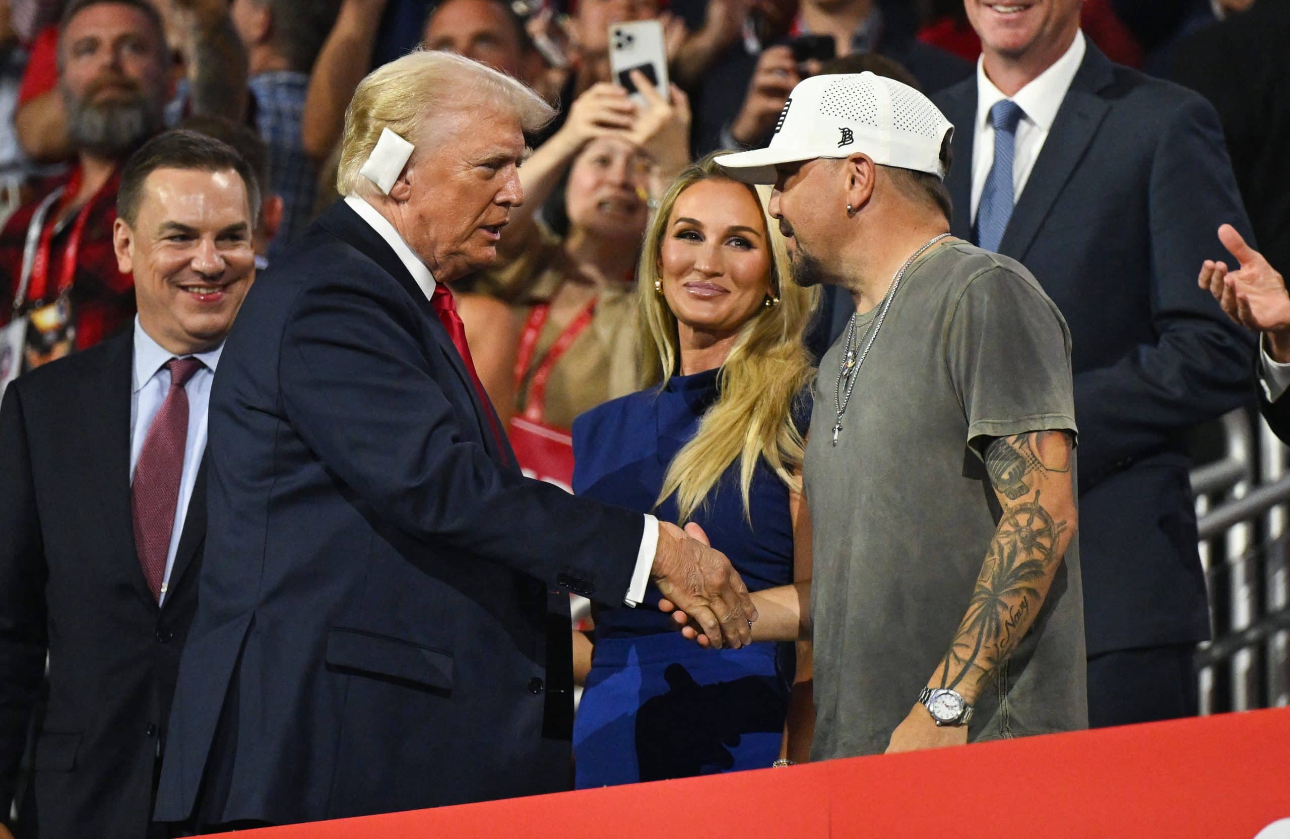 US former President and 2024 Republican presidential candidate Donald Trump shakes hands with US singer Jason Aldean as his wife singer Brittany Kerr looks on, on the last day of the 2024 Republican National Convention at the Fiserv Forum in Milwaukee, Wisconsin, on July 18, 2024. Donald Trump will get a hero's welcome Thursday as he accepts the Republican Party's nomination to run for US president in a speech capping a convention dominated by the recent attempt on his life. (Photo by Patrick T. Fallon / AFP) (Photo by PATRICK T. FALLON/AFP via Getty Images)