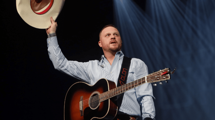 Cody Johnson on stage lifting his hat in the air in Arizona
