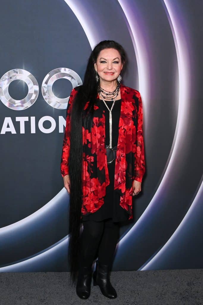 Crystal Gayle in a red and black outfit on the Opry 100 red carpet.