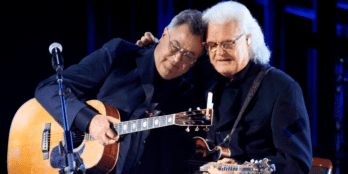 Ricky Skaggs embraces Vince Gill after singing with him on the "opry 100" tv special.